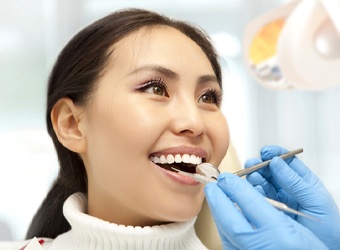 Woman in dental chair at cleaning and checkup appointment.