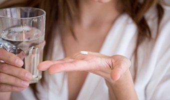 Woman with a glass of water and pill in her hand