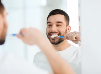 Man smiling while brushing his teeth
