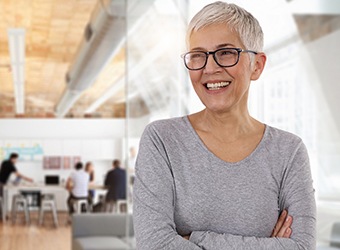 Woman in grey shirt smiling with dental implants in Prince Albert