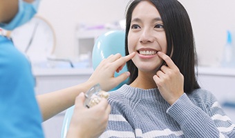 Woman pointing to her dental implant restorations during appointment