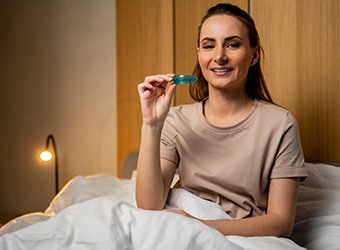 Woman in bed, holding an oral appliance