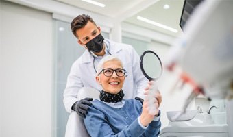 a patient checking her dental implants with a mirror