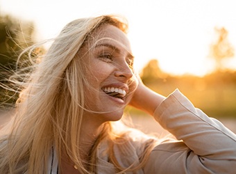 Woman with dental implants in Prince Albert outside and smiling