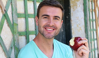 Man with dental implants in Prince Albert eating an apple