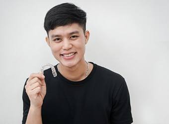 young man holding an Invisalign clear aligner 