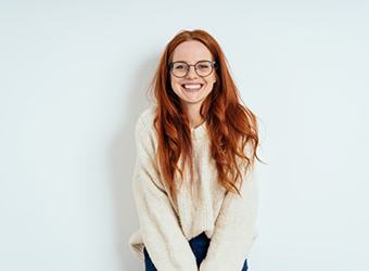 a red-haired woman in a sweater smiling
