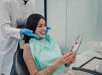 Woman smiling at reflection in handheld mirror