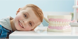 young boy smiling next to large teeth