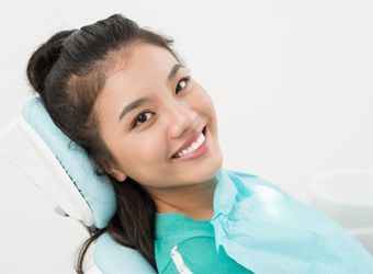 Female patient leaning back in dental chair and smiling