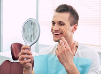 Man checking his smile in a handheld mirror