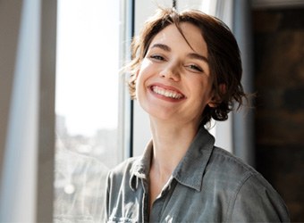 Woman standing by a window and smiling