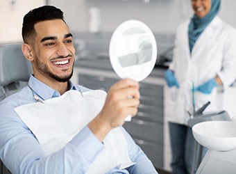 Patient smiling at reflection in handheld mirror