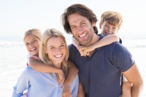 family of four smiling hugging