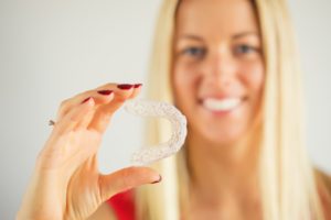 attractive woman smiling holding Invisalign tray