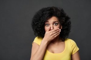 Woman covers her mouth after her dental crown breaks