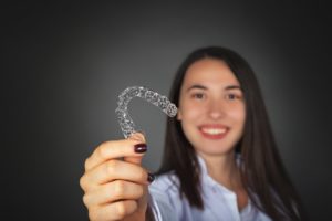 Woman holding a clear aligner for Invisalign in Prince Albert.