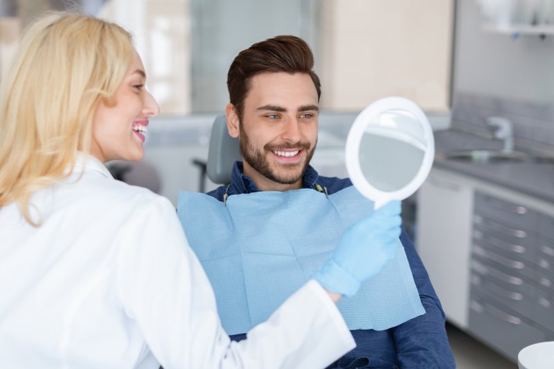A smiling patient admiring the results of his cosmetic dentistry